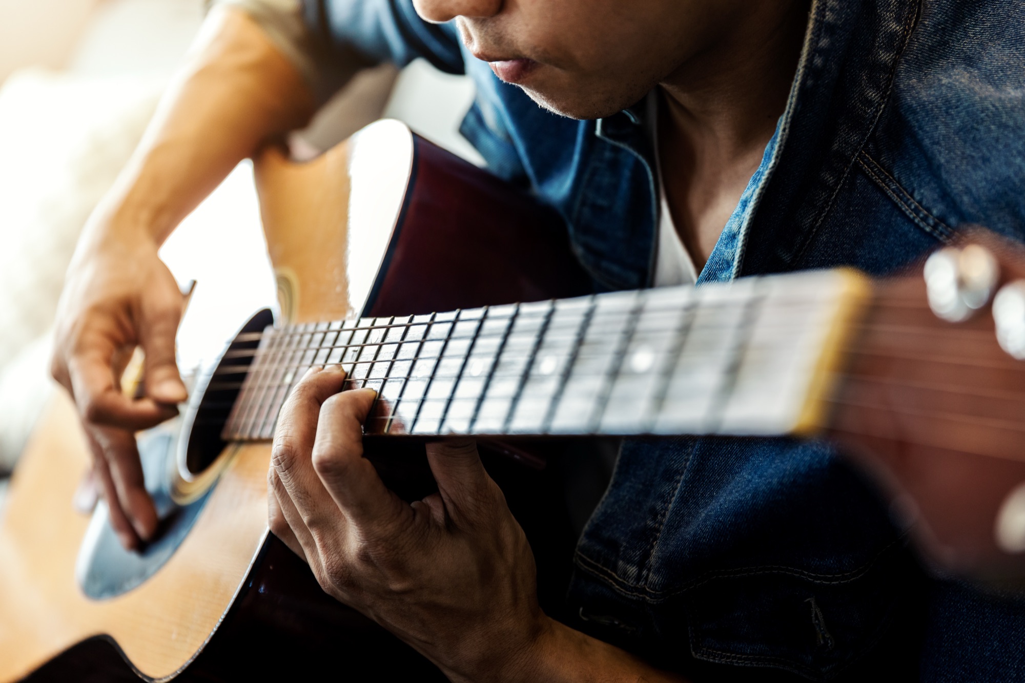 Hands working on an acoustic guitar.
