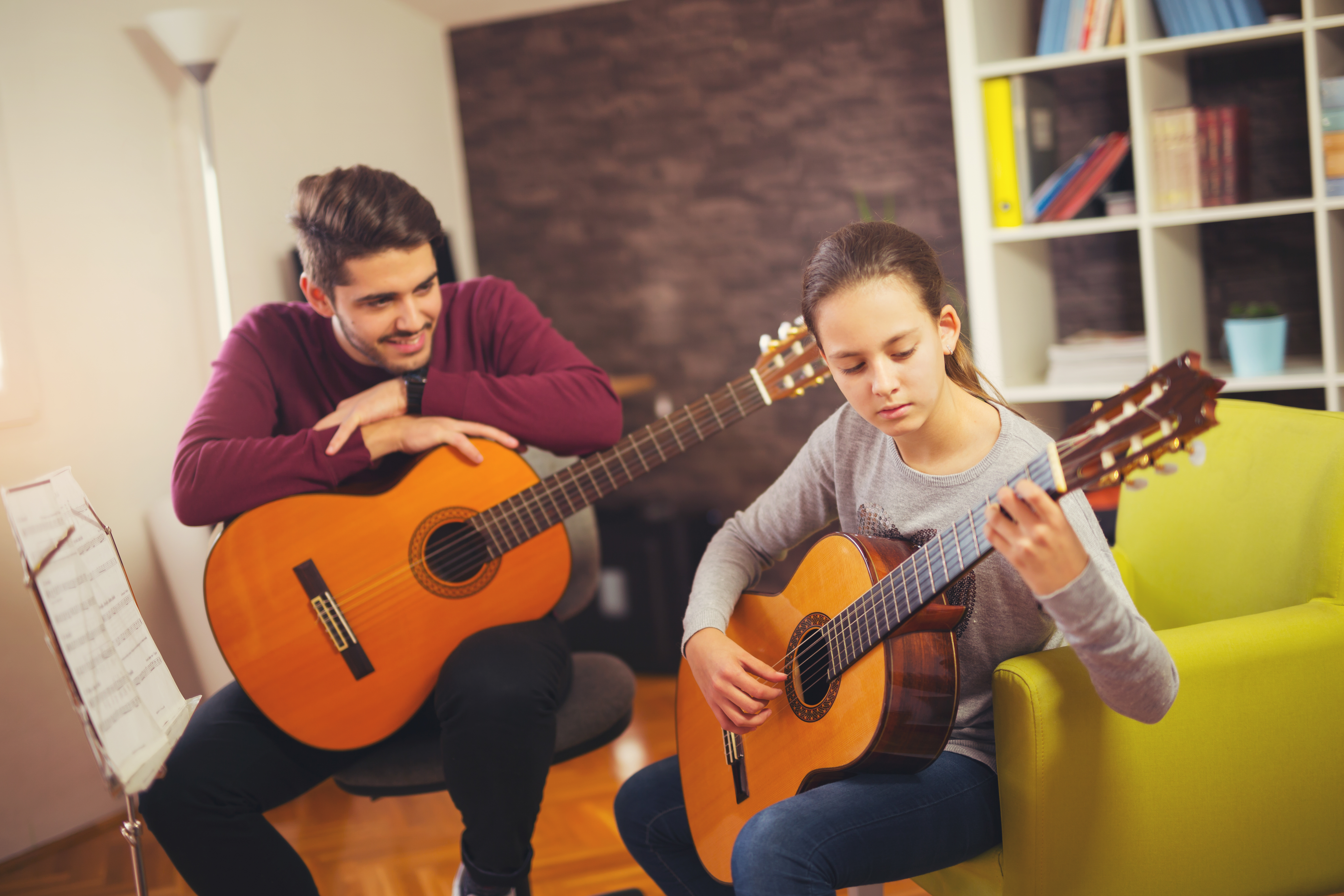 A teacher and student together with their guitars.