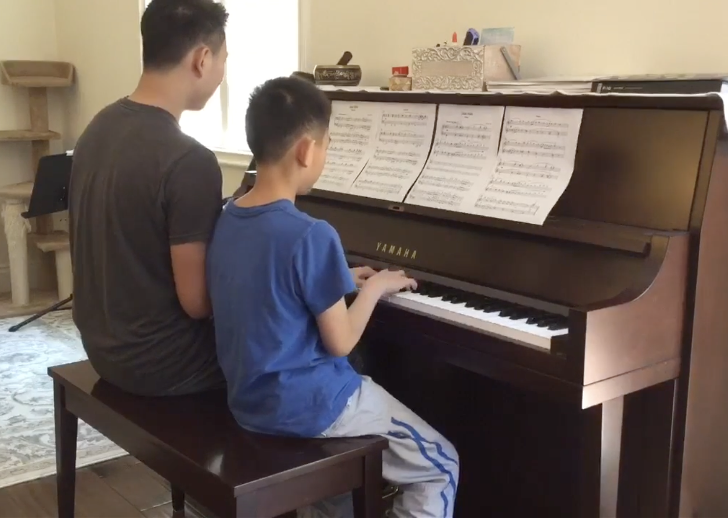 Two students working together at a piano at home.