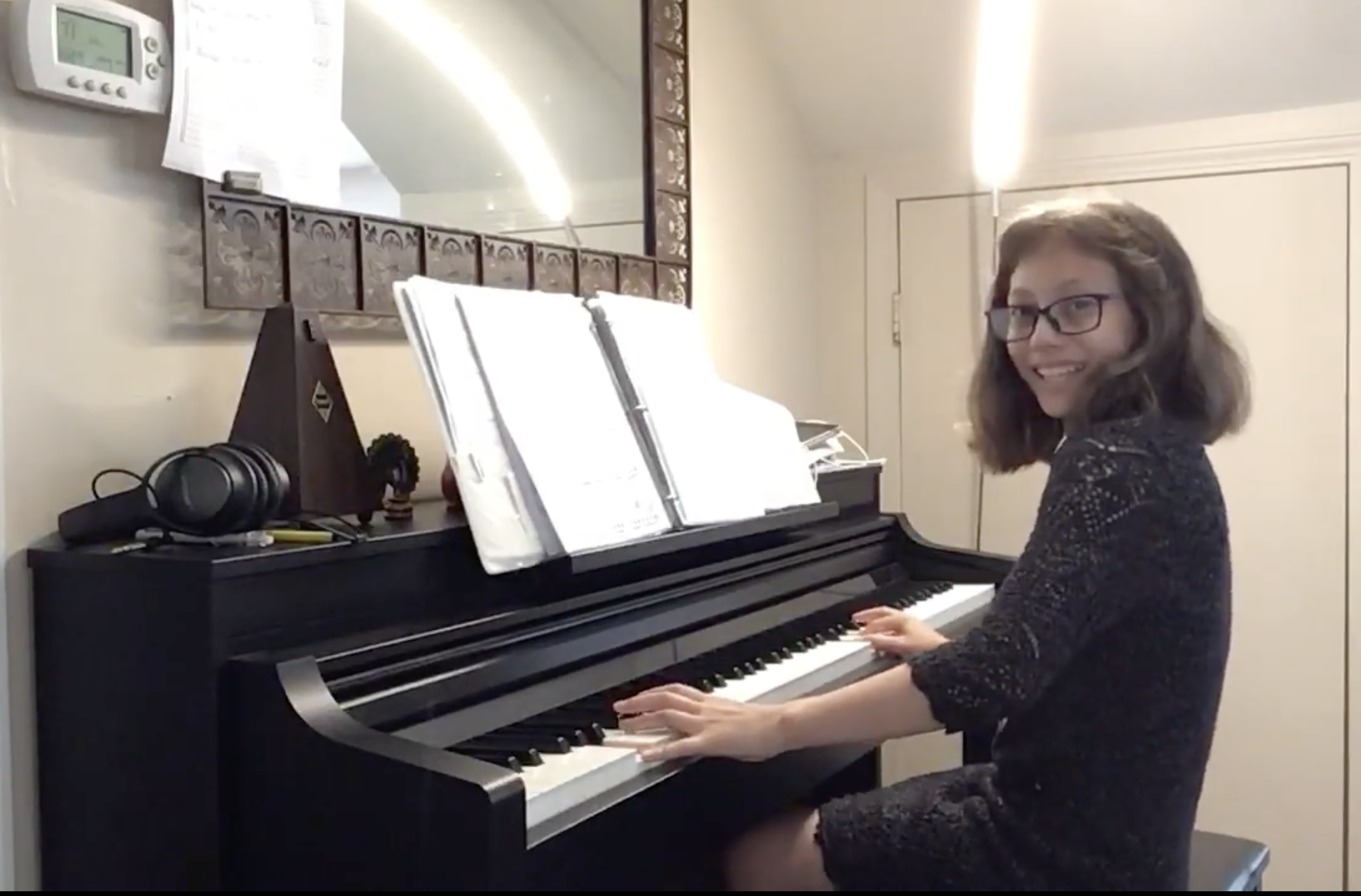 A smiling piano student with her instrument at home