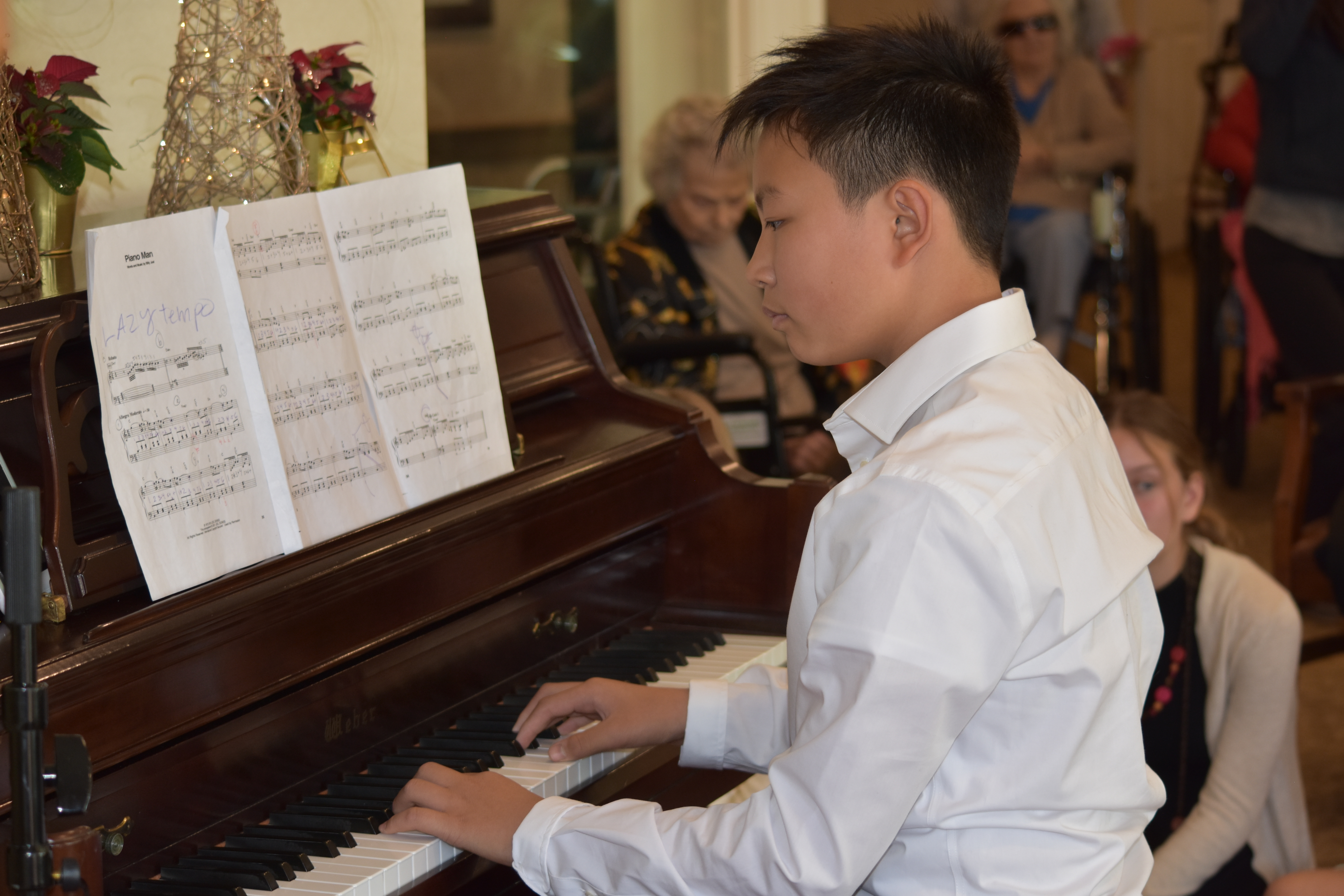 A student playing piano, with music open on the stand.