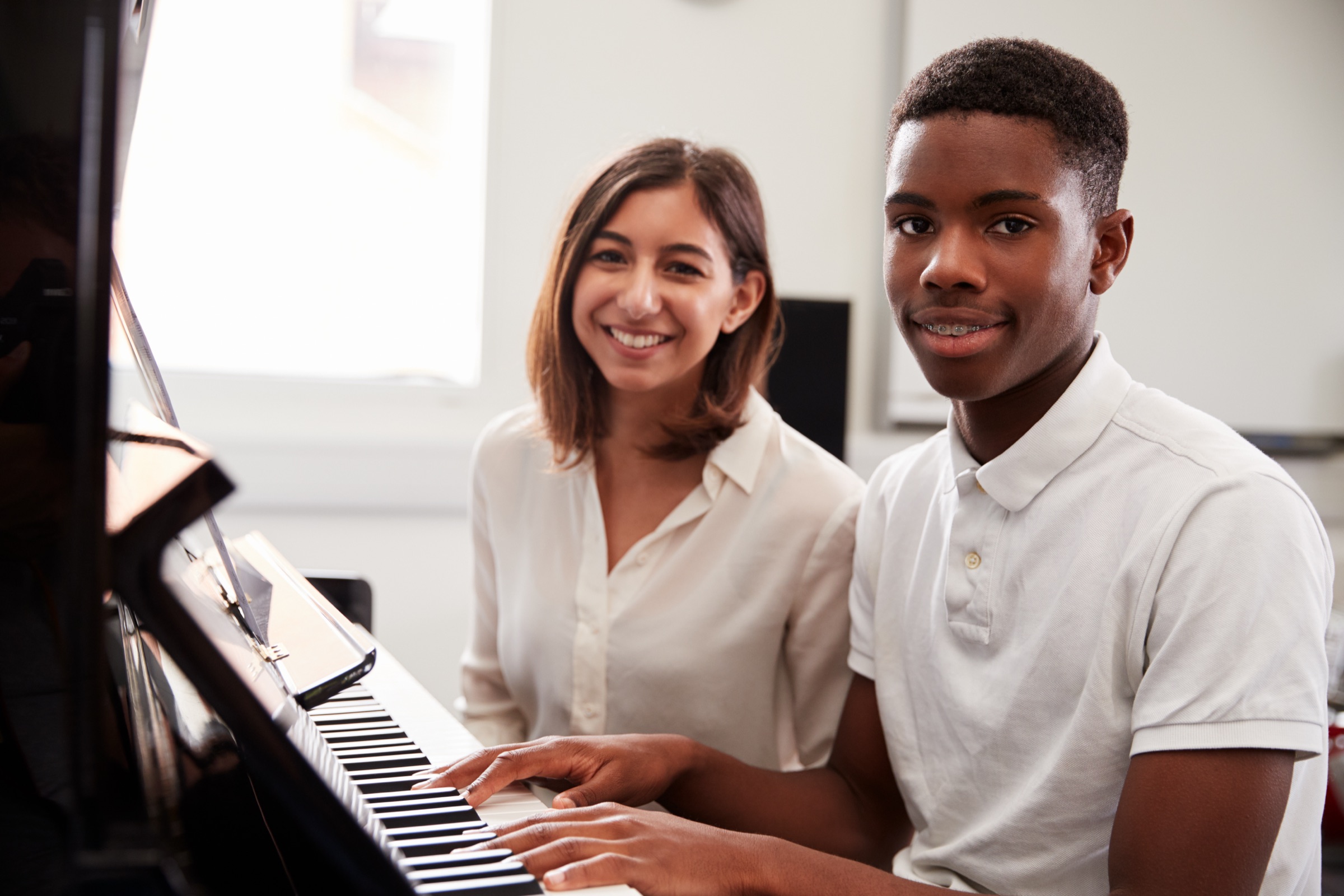 A teacher and student working together at the piano.