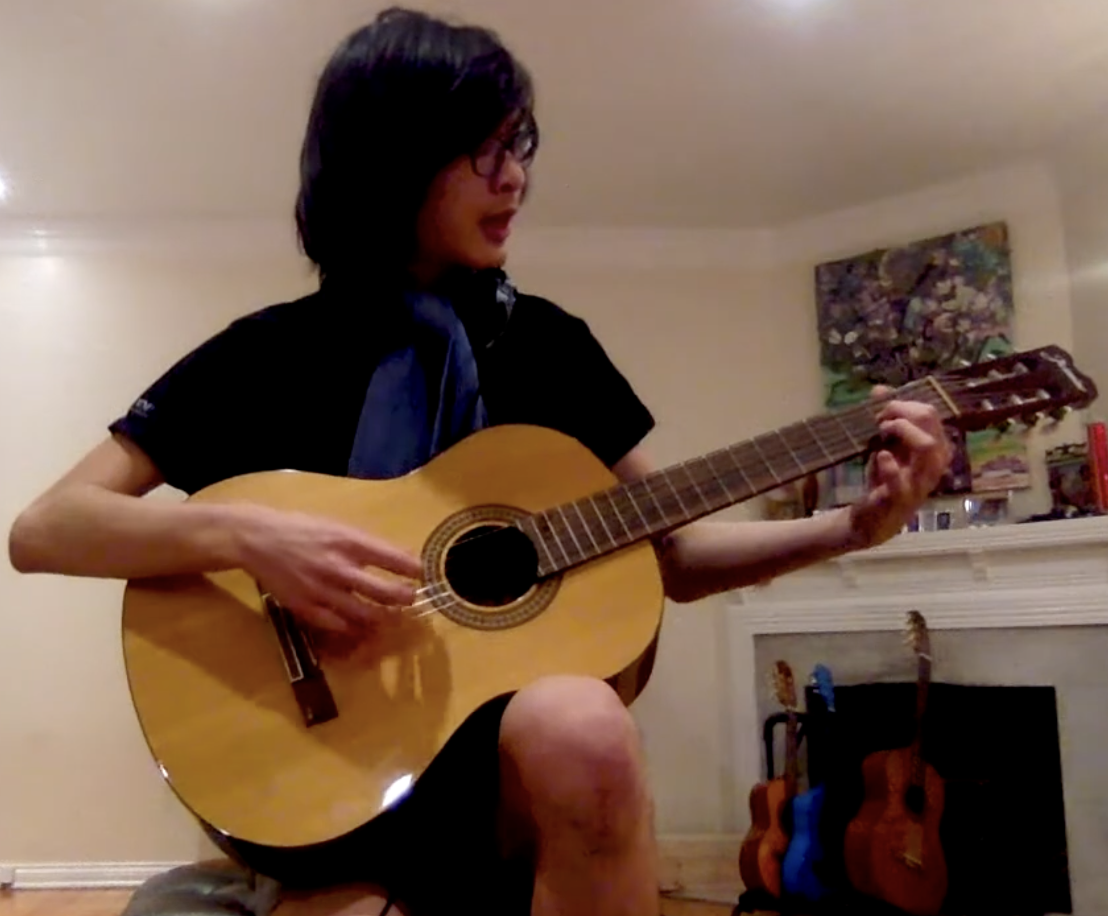 A student playing an acoustic guitar at home.